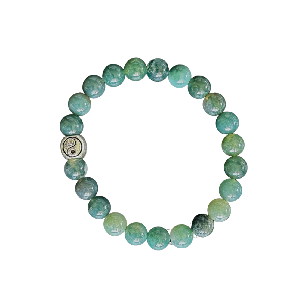 Green beaded bracelet with a silver charm on a clear background